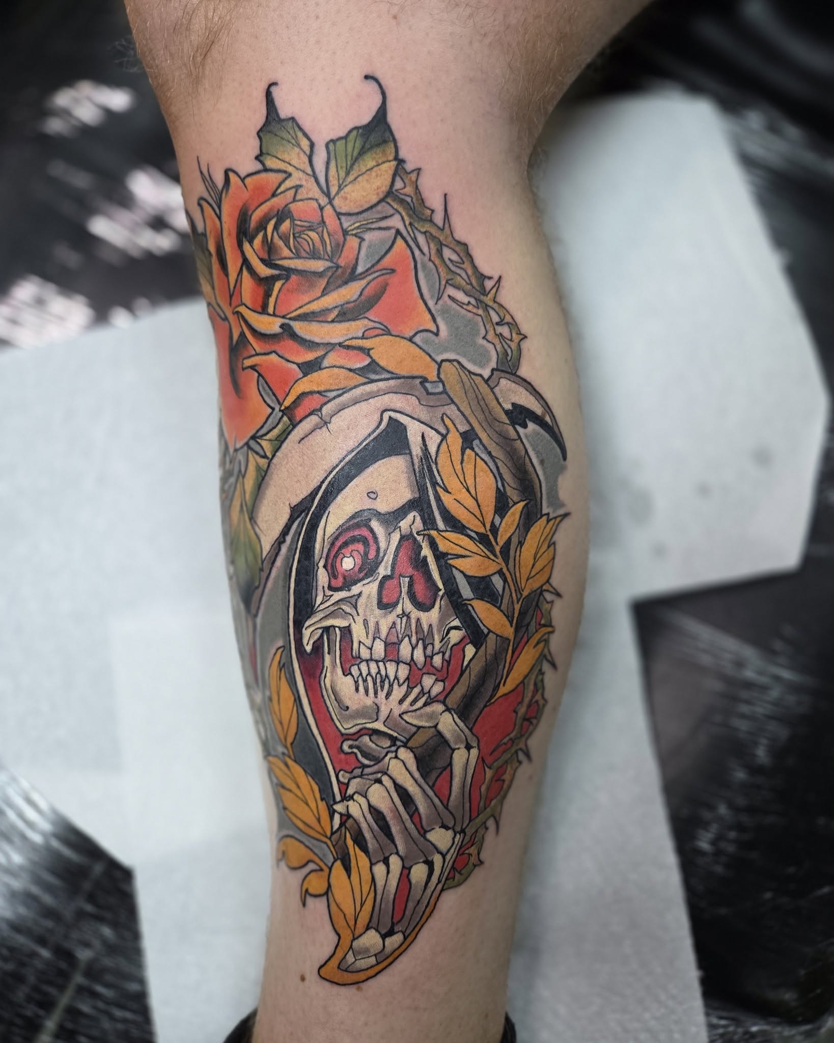 Close detail of Dan’s colour tattoo: a hooded skull beneath an orange rose and gold leaves