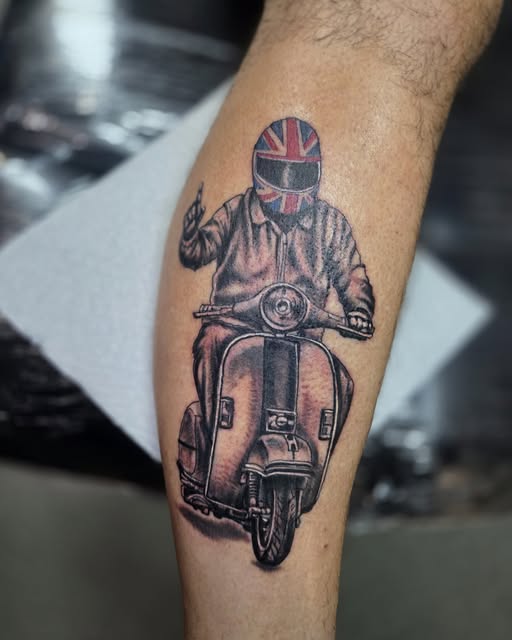 Detailed scooter rider tattoo with black-and-grey shading and a Union Jack helmet